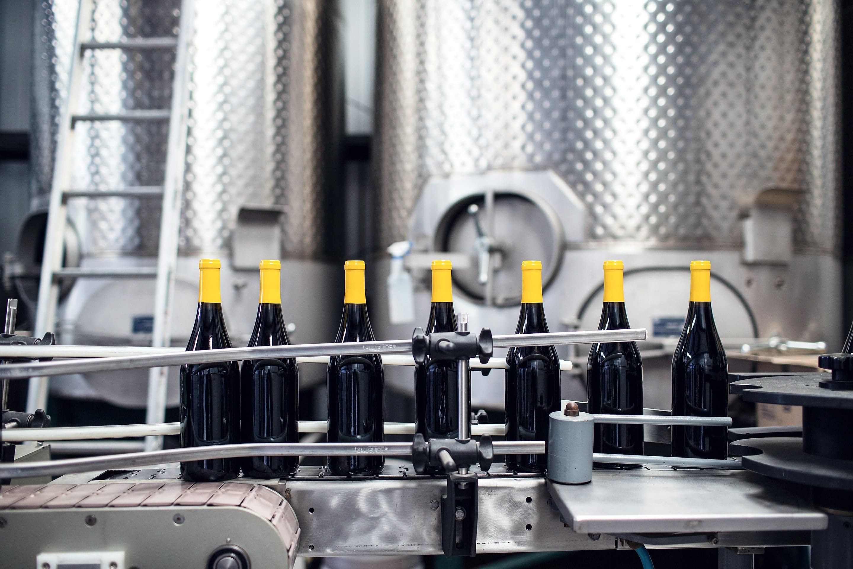 Unlabelled bottles with yellow capsules on a bottling line